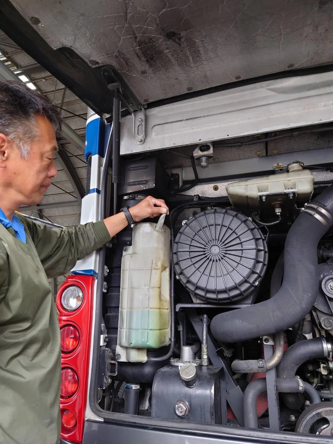 Technician installing FuelMarble mineral pack in the coolant expansion tank of a Yamanashi Kotsu diesel bus, Japan